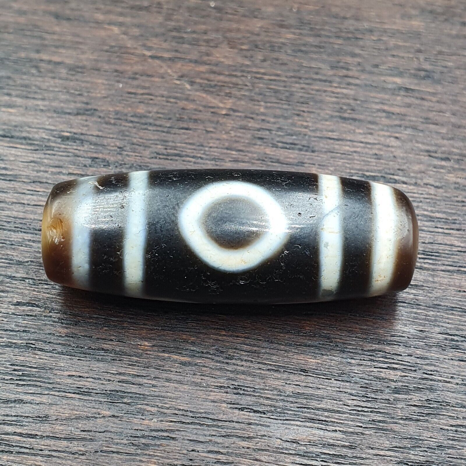 "Vintage Tibetan Dzi bead featuring three circular 'eyes' in a rare and highly prized 'Eye in Eye' Agate stone design, considered a powerful and protective amulet in Tibetan culture. This high-quality bead is said to bring good fortune, prosperity, and spiritual growth to its wearer."
