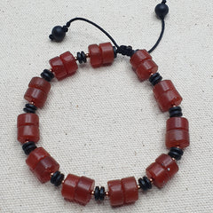 Carnelian Agate Beaded bracelet with red and black beads on a beige fabric background