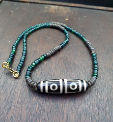 "Four Eyes Pattern Antique Black Tibetan Agate Dzi Bead Amulet Necklace: A rare and sacred vintage necklace featuring a handcrafted black Tibetan agate Dzi bead with a four eyes pattern, believed to bring spiritual protection and good fortune. The bead has a smooth,