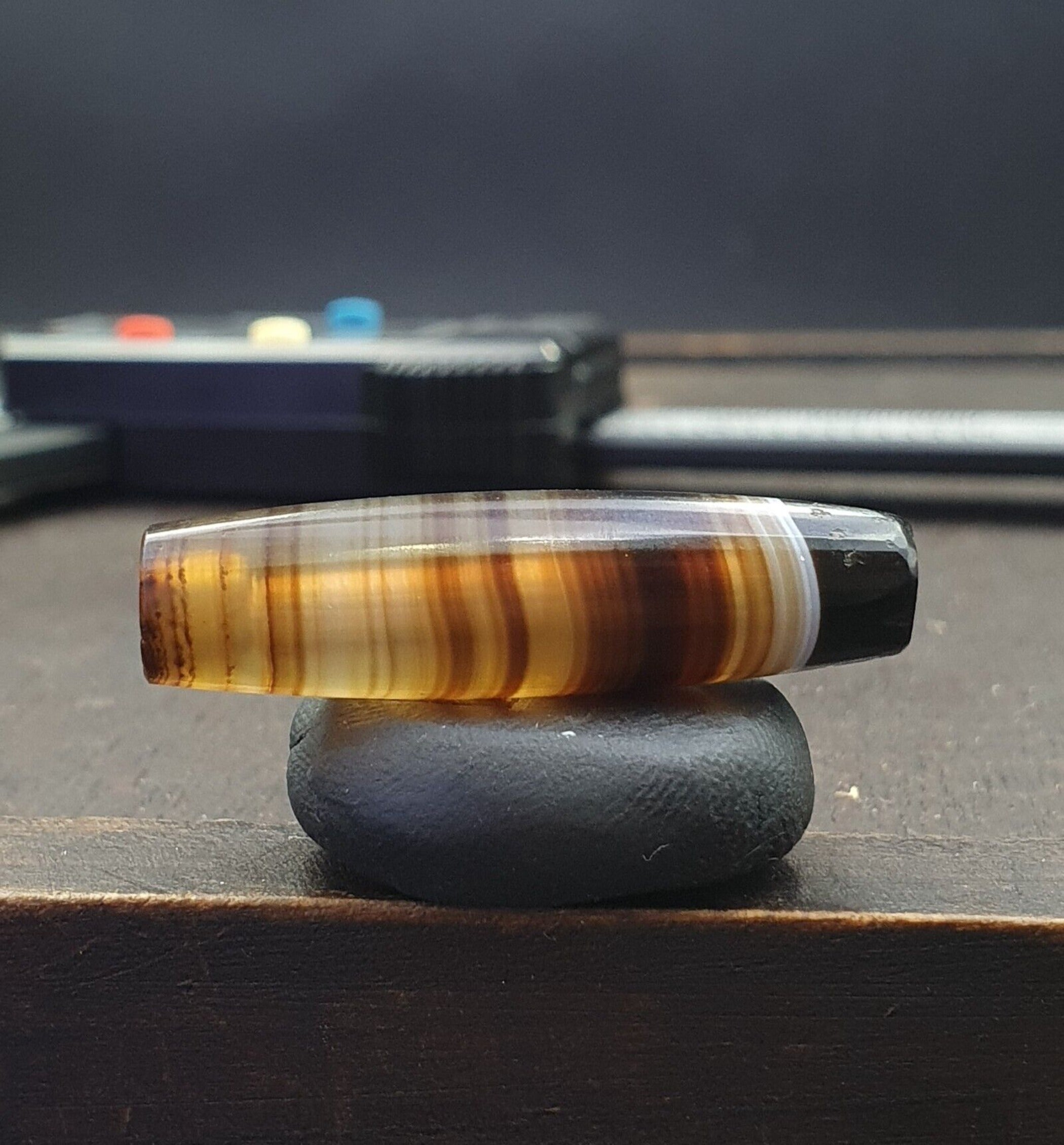 "Antique Old Yemeni Agate Bead: A rare and unique banded agate bead featuring a natural, intricate pattern of alternating bands in shades of white, gray, and brown. The bead has a smooth, polished surface and an irregular shape, with a warm, earthy tone that hints at its age and authenticity. The banded pattern is characteristic of high-quality Yemeni agate, prized for its beauty and rarity."
