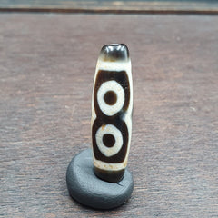 "Unique three-eyed agate bead from the Himalayas, featuring an intricate pattern and believed to possess spiritual powers, a rare find for collectors and enthusiasts."